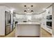 Bright kitchen featuring white cabinets, stainless steel appliances, quartz countertops and a center island at 10744 Drummond Rd, Tampa, FL 33615