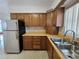 Cozy kitchen featuring wood cabinets, a stainless steel refrigerator, and a double-basin sink at 11735 86Th Ave, Seminole, FL 33772