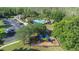 Aerial view of neighborhood amenities with a community pool, playground, and clubhouse nestled among green trees at 12136 Luftburrow Ln, Hudson, FL 34669