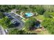 Aerial view of community amenities including a pool, playground, parking, and a recreation building surrounded by lush trees at 12136 Luftburrow Ln, Hudson, FL 34669