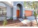 Close up of an inviting front exterior, with orange door and garage, and landscaped garden bed at 12136 Luftburrow Ln, Hudson, FL 34669