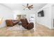 Spacious living room featuring tile floors, a ceiling fan, and comfortable brown leather seating at 12136 Luftburrow Ln, Hudson, FL 34669