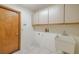 Functional laundry room with white cabinets, utility sink, and tile flooring at 1228 Rainbrook Cir, Valrico, FL 33596