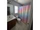 Bathroom with neutral walls, tile floors, single sink vanity, and rainbow patterned shower curtain at 13157 Kings Crossing Dr, Gibsonton, FL 33534