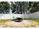 Serene backyard seating area with comfortable chairs surrounding a fire pit, enclosed by a white fence at 13803 Chalk Hill Pl, Riverview, FL 33579