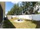 Backyard with green grass, a white fence, fire pit, shed and two Adirondack chairs at 13803 Chalk Hill Pl, Riverview, FL 33579