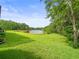 Expansive backyard showcasing lush green grass leading to a serene lake surrounded by trees at 14134 Trouville Dr, Tampa, FL 33624