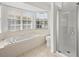Bright bathroom featuring a large bathtub, a glass shower and tiled floors at 14134 Trouville Dr, Tampa, FL 33624