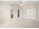 Bright, carpeted bedroom with ceiling fan, closet, and access to bathroom and staircase at 14134 Trouville Dr, Tampa, FL 33624