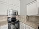 Close up on the black stove with a stainless steel microwave above and granite counter tops at 14134 Trouville Dr, Tampa, FL 33624