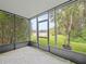 Enclosed porch with leaf pattern flooring, screening and an exterior view showcasing lush greenery and a lake at 14134 Trouville Dr, Tampa, FL 33624
