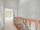 View of a staircase with wooden railing leading to a carpeted hallway and an open, light-filled room at 14134 Trouville Dr, Tampa, FL 33624