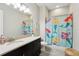 Charming bathroom with a mermaid-themed shower curtain, black vanity, and neutral walls at 14715 Fishhawk Preserve Dr, Lithia, FL 33547
