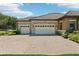 Three-car garage featuring stone accents, a spacious driveway, and well-maintained landscaping at 14715 Fishhawk Preserve Dr, Lithia, FL 33547