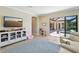 Bright playroom features a TV, display cabinet, blue rug, comfortable seating, and access to a patio and pool at 14715 Fishhawk Preserve Dr, Lithia, FL 33547