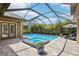 Beautiful screened-in pool area with a spa, brick patio, and outdoor lounge chairs at 14715 Fishhawk Preserve Dr, Lithia, FL 33547