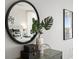 Close-up of a stylish dresser with decorative objects, including a round mirror and plant at 17920 Gulf Blvd # 1806, Redington Shores, FL 33708
