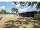 Spacious backyard featuring a white fence, palm trees, screen enclosed lanai, and ample space for outdoor activities at 1818 Willow Oak Dr, Palm Harbor, FL 34683