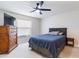Comfortable bedroom with a blue bedspread, carpeted floor, and dresser with TV at 1818 Willow Oak Dr, Palm Harbor, FL 34683