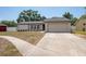 Well-maintained single-story home with a two-car garage, manicured lawn, and a tidy walkway to the entrance at 1818 Willow Oak Dr, Palm Harbor, FL 34683