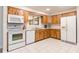 Well-lit kitchen with tile flooring, white appliances, wood cabinetry, and a window over the sink at 1818 Willow Oak Dr, Palm Harbor, FL 34683