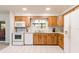 Bright kitchen with white appliances, wood cabinetry, and a window offering natural light at 1818 Willow Oak Dr, Palm Harbor, FL 34683