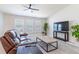 Cozy living room with a leather sofa, ottoman, and modern TV, perfect for relaxing and entertaining at 1818 Willow Oak Dr, Palm Harbor, FL 34683