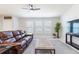 Comfortable living room featuring a brown leather sofa, ottoman, a ceiling fan and ample natural light at 1818 Willow Oak Dr, Palm Harbor, FL 34683