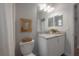 Bathroom features a white vanity with granite countertops, framed mirror, decor, and a toilet with framed artwork above at 212 Villa Luna Ln, Lutz, FL 33549