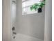 Shower and tub combination features a white tile surround, silver fixtures, curtain, and a window with a leafy plant at 212 Villa Luna Ln, Lutz, FL 33549