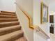 Carpeted staircase featuring a wood handrail and decorative artwork along the wall, creating a warm ambiance at 3138 Nautical S Pl, St Petersburg, FL 33712