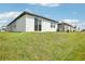Exterior of a modern home with sliding glass doors, manicured lawn, and partial view of neighborhood at 31647 Malbec Dr, Brooksville, FL 34602