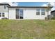 Exterior of a modern home with sliding glass doors, manicured lawn, and partial view of neighborhood at 31647 Malbec Dr, Brooksville, FL 34602