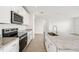 A modern kitchen featuring white cabinets, granite countertops, stainless steel appliances and wood-look tile flooring at 31647 Malbec Dr, Brooksville, FL 34602