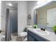 Bathroom with a tiled shower, blue vanity with a white sink, mirror, and neutral walls at 3703 Treeline Dr, Valrico, FL 33596