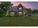 Beautiful two-story home featuring a metal roof, manicured lawn, and a lovely screened-in front porch at dusk at 37309 Fountain Rd, Zephyrhills, FL 33542