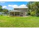Rear view of a charming two-story house with a metal roof, screened porch and a large backyard at 37309 Fountain Rd, Zephyrhills, FL 33542