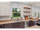 Traditional kitchen with granite countertops, open shelves, stainless steel dishwasher, and view to the yard at 37309 Fountain Rd, Zephyrhills, FL 33542
