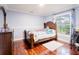 Cozy bedroom with wooden bed frame, hardwood floors, and a view of the lush backyard at 382 Florian Way, Spring Hill, FL 34609