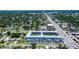 Wide aerial view of light blue condo building with parking, set amongst greenery and neighborhood, with street nearby at 4050 4Th N St # 205, St Petersburg, FL 33703