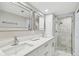 Bright bathroom featuring double sinks, stone countertop, and a walk-in shower with stone flooring at 4203 W Cleveland St, Tampa, FL 33609