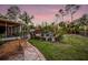 Backyard oasis with a sparkling pool, lush landscaping, and a pink sunset at 4301 S Lockwood Ridge Rd, Sarasota, FL 34231