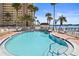 Community pool featuring waterfront access, lounge chairs, and mature palm trees under a sunny blue sky at 4550 Cove Cir # 1003, St Petersburg, FL 33708