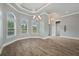 Bright, airy living room with wood floors, tray ceiling, arched windows, and elegant chandelier at 602 Swilley Rd, Plant City, FL 33567