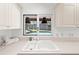 White kitchen sink with view to pool and backyard through sliding window at 6101 Willow Oak Cir, Bradenton, FL 34209