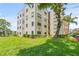 Exterior view of condo building, featuring manicured lawn and mature trees at 6188 80Th N St # 101, St Petersburg, FL 33709