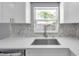 The kitchen boasts a stainless steel sink, mosaic backsplash, and a bright window for natural light at 6309 7Th Ave, New Port Richey, FL 34653