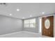 Bright living room with marble floors, recessed lighting, neutral paint, and decorative front door at 6309 7Th Ave, New Port Richey, FL 34653