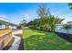 A backyard with lush green grass, landscaping, and a white fence under a clear blue sky at 6490 22Nd S St, St Petersburg, FL 33712