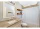 Well lit bathroom featuring a white vanity, decorative floating shelves, and shower with white curtain at 6490 22Nd S St, St Petersburg, FL 33712